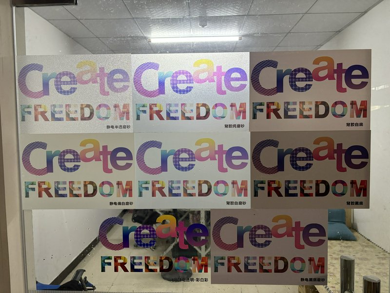 Colorful posters with the word "Create" and "Freedom" repeated across a glass window.