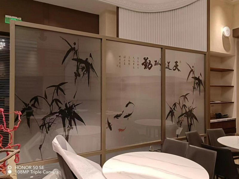 Restaurant interior with frosted glass dividers featuring bamboo artwork and Chinese calligraphy.