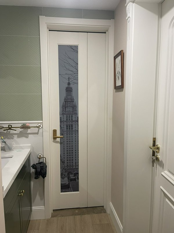Bathroom door with a tall vertical window showing a grayscale cityscape scene.