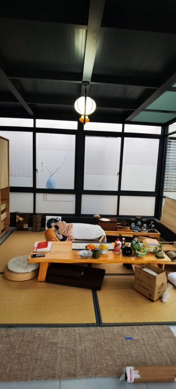 A cozy Japanese-style room with a low wooden table on tatami mats and a person resting on cushion...