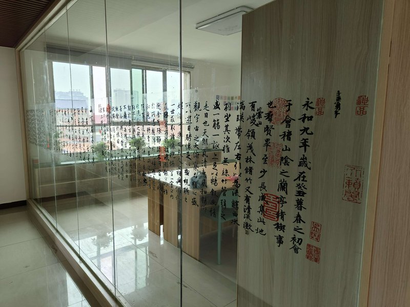 Glass-walled office interior adorned with Chinese calligraphy and red seal stamps.