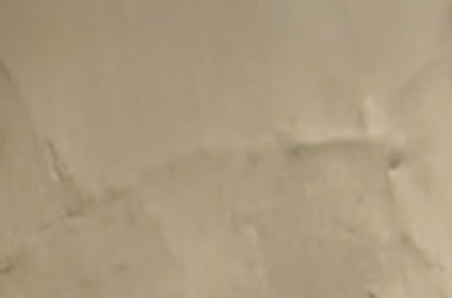Blurry close-up of water-damaged drywall ceiling with cracked, peeling, discolored plaster patches