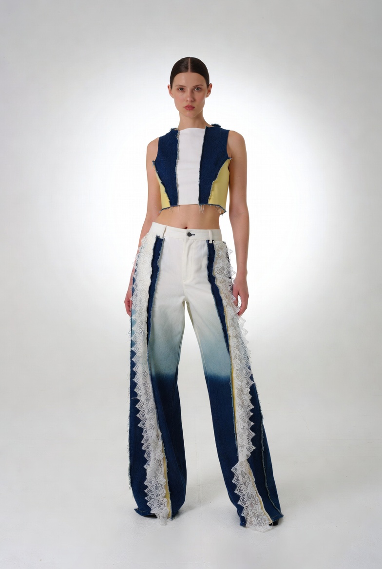 Model wearing a color-blocked crop top and gradient blue-to-white wide-leg pants with lace trim.