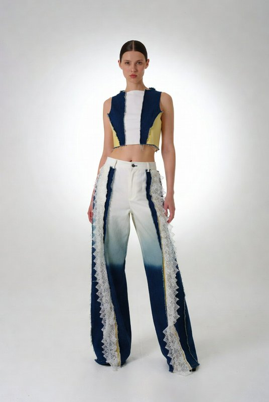 Model wearing a color-blocked crop top and gradient blue-to-white wide-leg pants with lace trim.