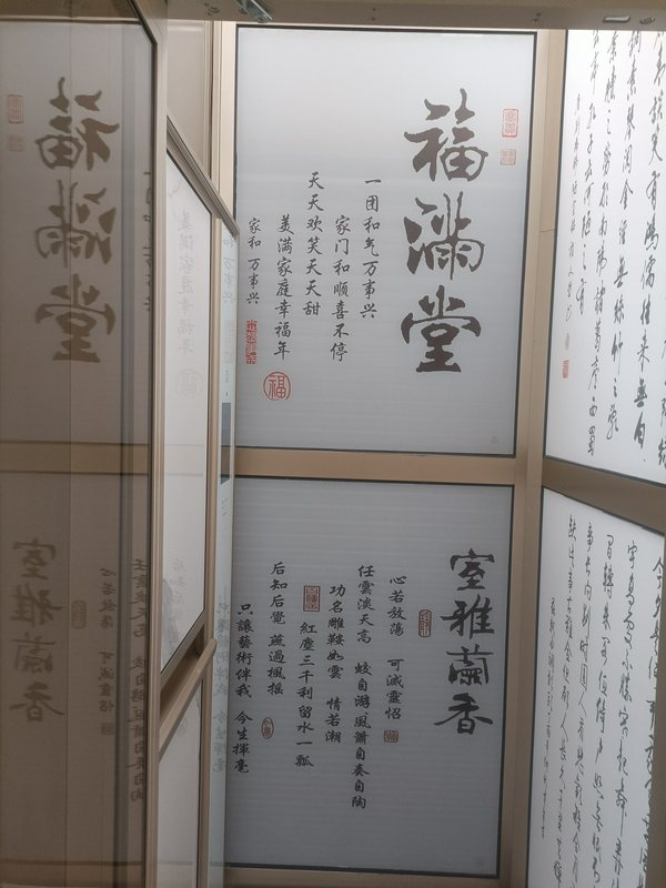 Interior of a room with glass walls displaying large Chinese calligraphy characters and red seals.