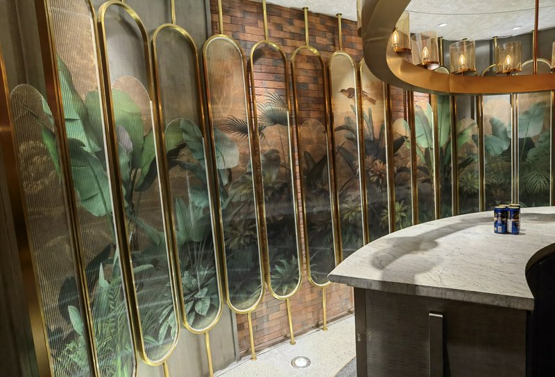 Marble bar with gold-framed glass panels depicting tropical plant artwork.