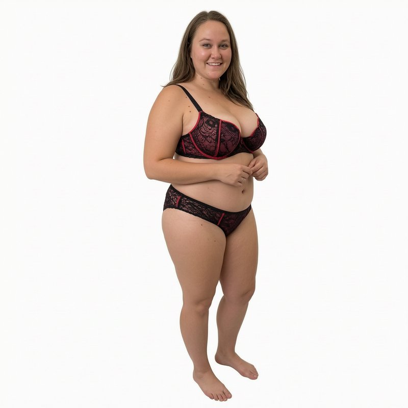 Smiling curvy plus-size woman wearing black and red lace lingerie against a plain white studio ba...