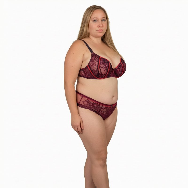 Plus size model wearing burgundy lace lingerie set standing against a plain white studio background