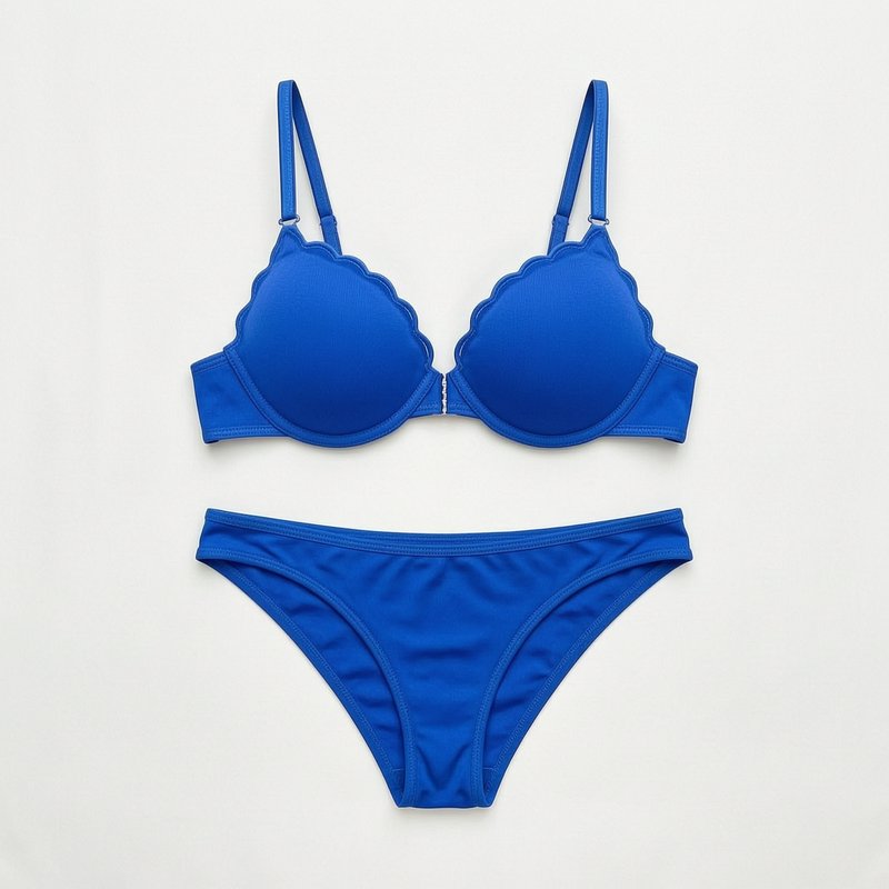 Bright cobalt blue scallop-edge two piece bikini set arranged flat on a plain off-white studio ba...